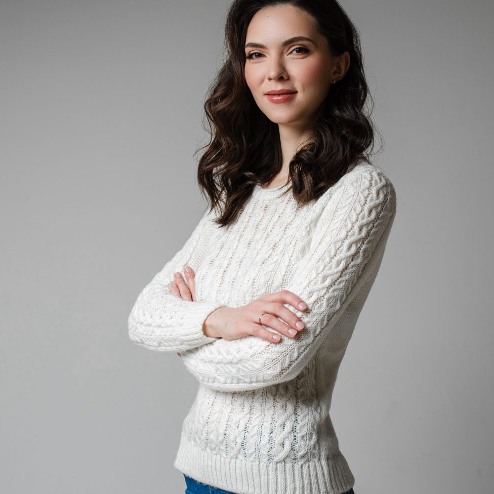 attractive female with dark hair in short white blouse smiles